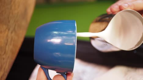 close-up of a barista pouring milk into a blue mug for coffee