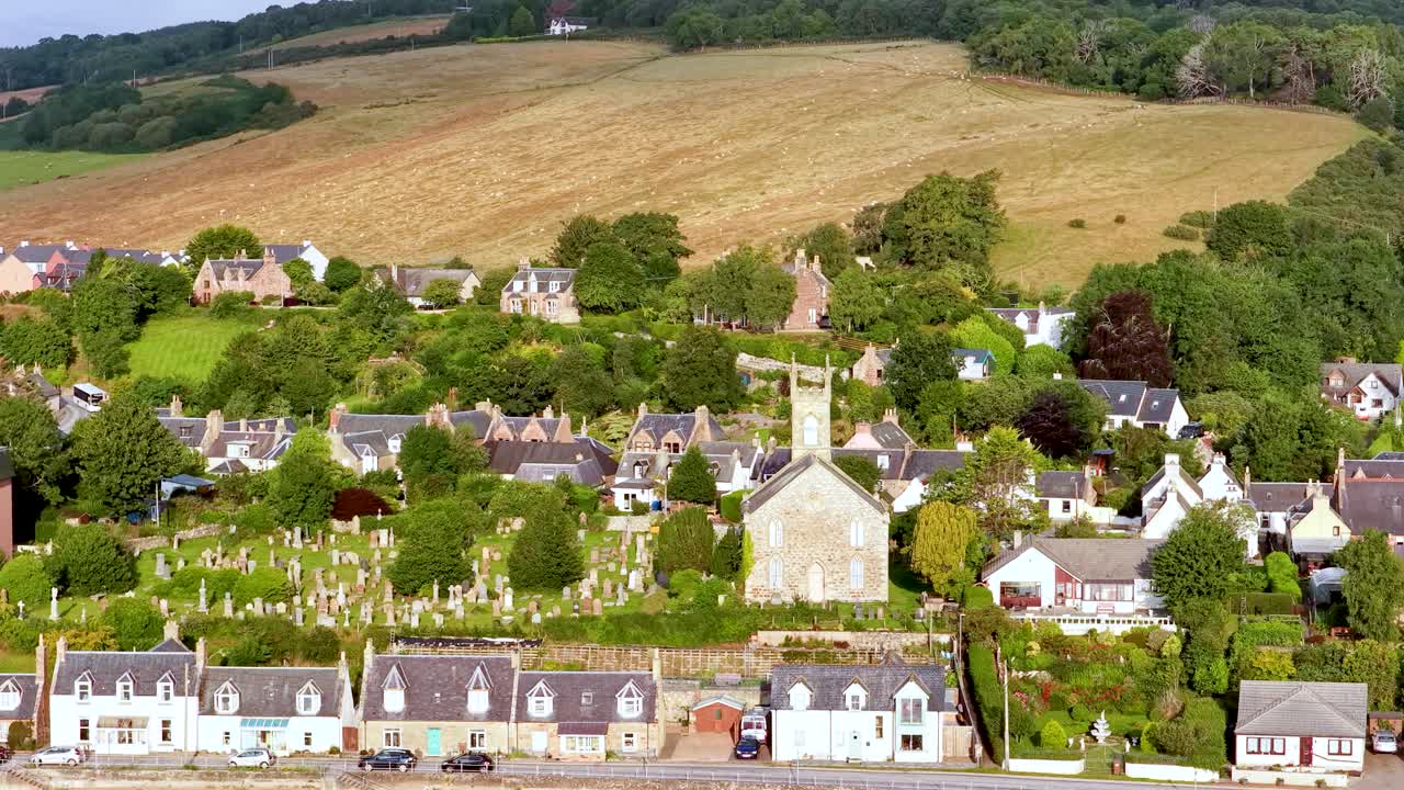 Drönare sveper ovanför Rosemarkie och framhäver kyrkan, kyrkogården, byns hem, grönskan och det lantliga landskapet