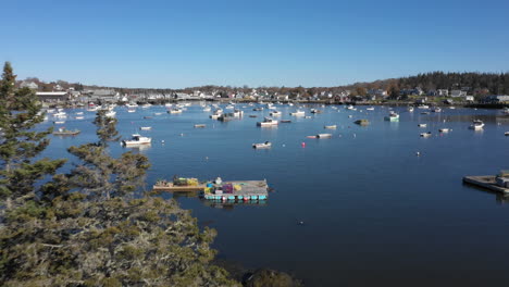 Aerial-Fly-Over-Reveal-Drone-Footage-over-tree-tops-revealing-parked-boats-on-Maine-Coast-at-Vinalhaven,-Fox-Islands,-Knox-County,-Maine,-USA