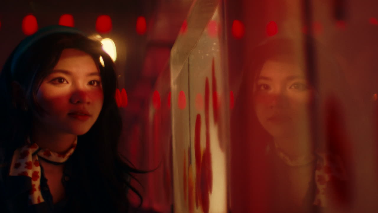 Woman looking at reflection in a red-lit aquarium
