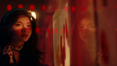 woman looking at reflection in a red-lit aquarium