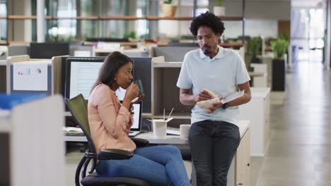 video of diverse businesswoman and businessman drinking coffee, eating and talking in office