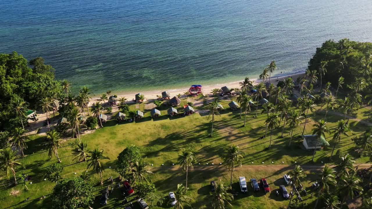 Aerial orbit of picturesque tropical island beach resort with turquoise ocean coastline and palm trees at Bagasbas, San Andres, Catanduanes.