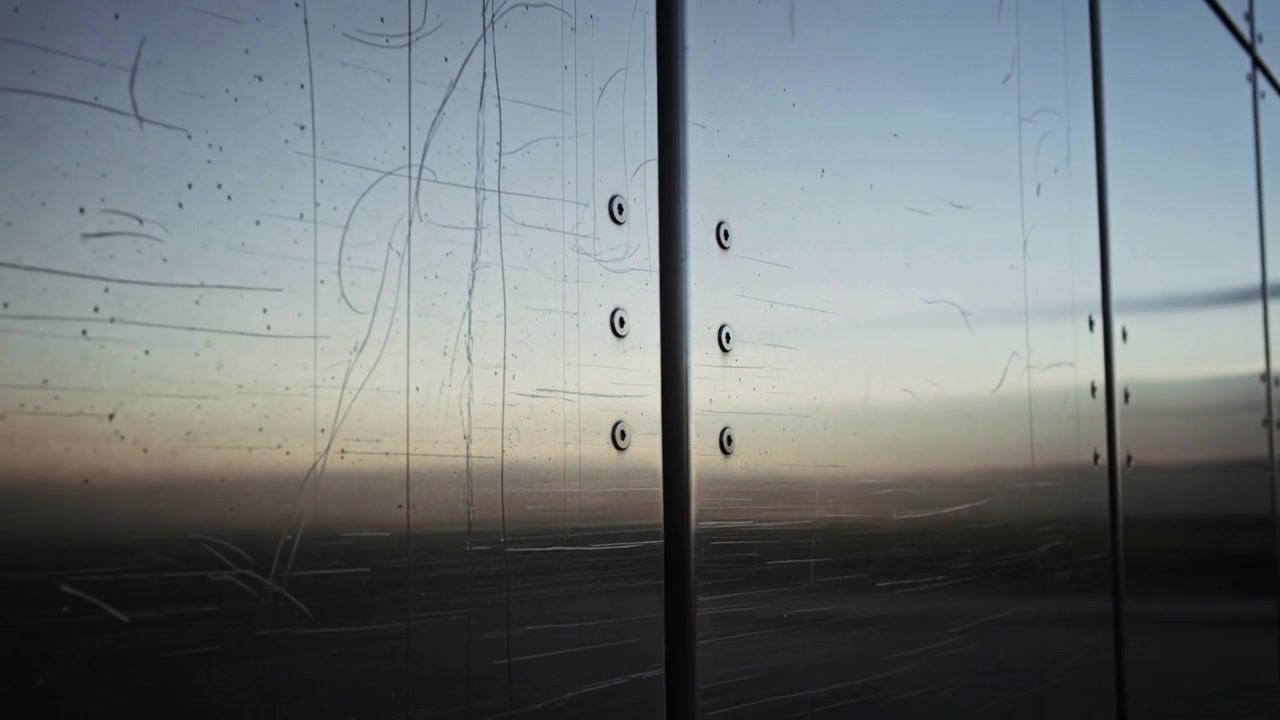 Panning camera revealing scratched glass pane with mullion rivets at deck showing cable and horizon
