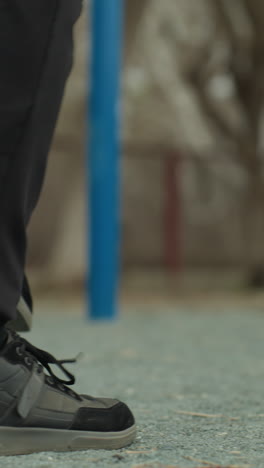 close-up of a person s legs jogging quickly, wearing black jeans and black sneakers, with a blurred view of blue iron bars in the background