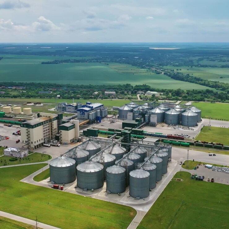 Grain elevators on beautiful landscape. Agricultural factory with granaries. Large aluminum containers for storing cereals. Aerial view.
