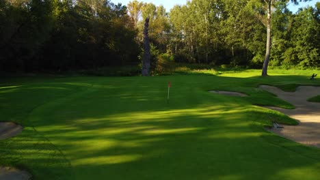 Statischer-Aufbau,-Drohnenschuss-Aus-Niedrigem-Winkel-Mit-Dem-Einschlagen-Des-Balls-Ins-Grün-Auf-Dem-Golfplatz,-Nahaufnahme