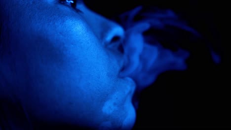 woman smoke in blue light, close up face and lips view