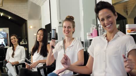 smiling hairdressers sitting on chair in salon
