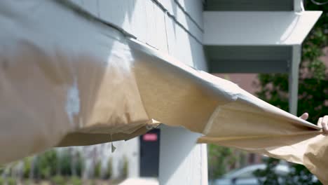 Painter-Removing-The-Brown-Paper-Covering-The-Concrete-Beam-Of-A-House-After-Painting---close-up