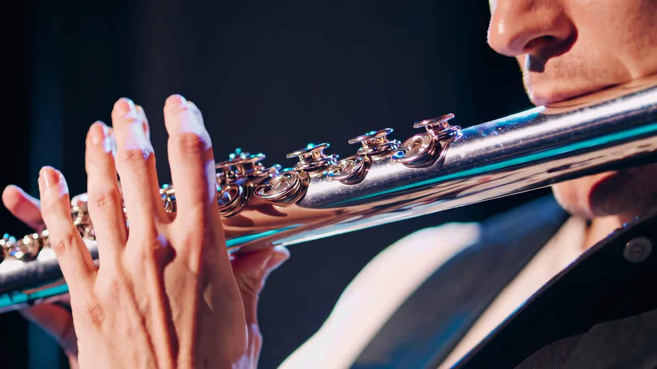 Close-up video shot of a musician playing a flute, focusing on hands and instrument
