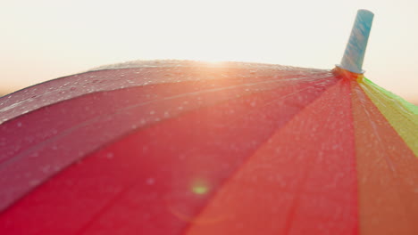 turning rainbow umbrella at sun shower closeup stylish colorful parasol rotates covering walker from