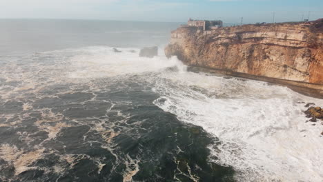 del fuerte de sao miguel arcanjo en nazare, portugal con olas que se estrellan