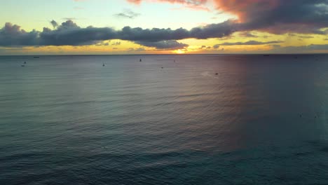 Drone-Volando-Sobre-Una-Flota-De-Veleros-En-Un-Amanecer-Hawaiano-Navegando-A-Través-De-Las-Olas-Del-Océano-Frente-A-La-Costa-De-La-Playa-De-Waikiki-En-Honolulu---Vista-Aérea