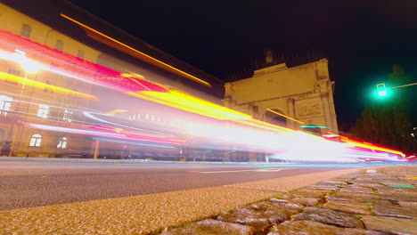 Low-angle-traffic-speeding-around-Victory-Arch-Siegestor-in-central-Munich,-Germany