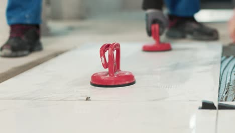 construction workers placing a huge tile on the ground with vacuum handles