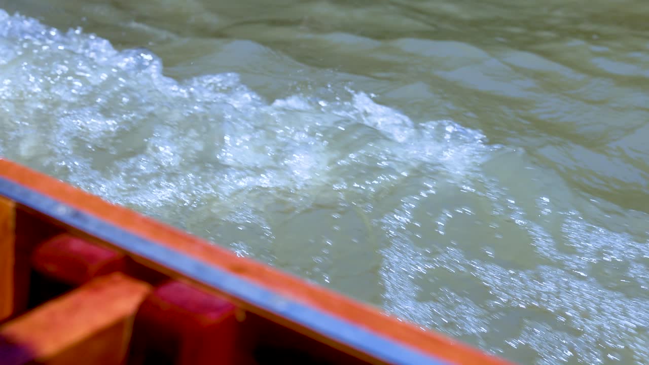 한 보트가 바쁜 방 운하를 항해하며, 자연의 낮빛에서 역동적인 물 스프레이와 활기찬 반사를 포착합니다.