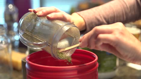 processed cannabis mixed with ingredients in a container to create herbal remedies - close up shot