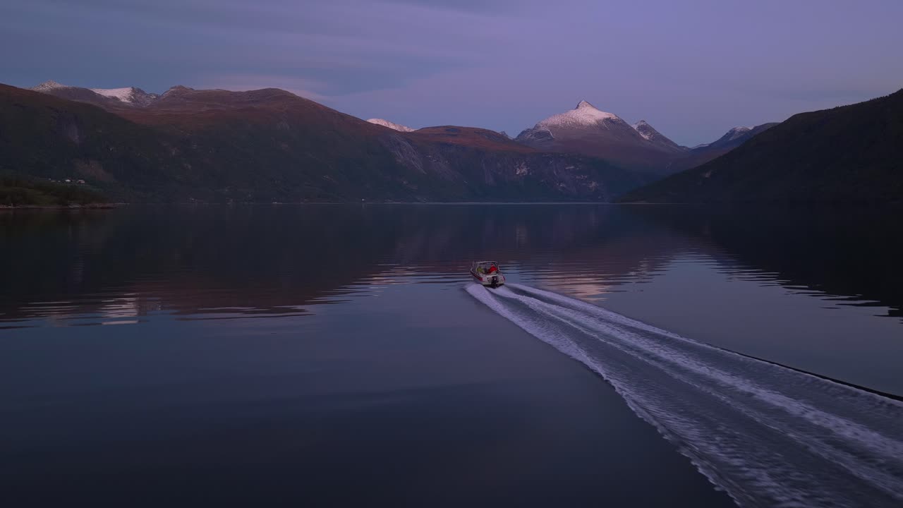 Vista da drone di motoscafo che sfreccia attraverso il Langfjorden al tramonto, Norvegia