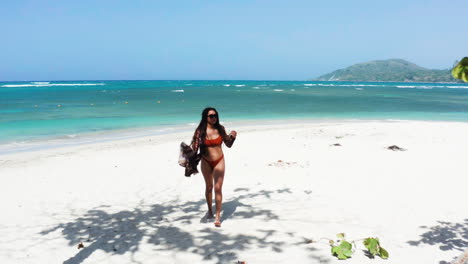 hispanic woman enjoys leisure getaway to secluded white sand beach paradise in caribbean, drone dolly out