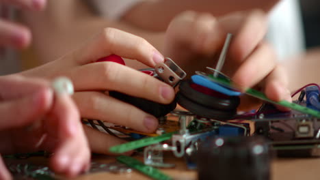 Marco-video-of-teenagers-hands-linking-different-details-on-wooden-table.