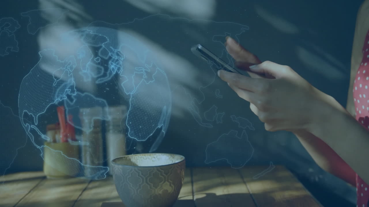 manos sosteniendo un teléfono inteligente sobre la animación del mapa del mundo en el fondo de la mesa de madera