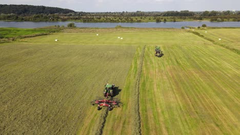 due trattori che lavorano insieme su un grande terreno agricolo verde che produce balle di fieno