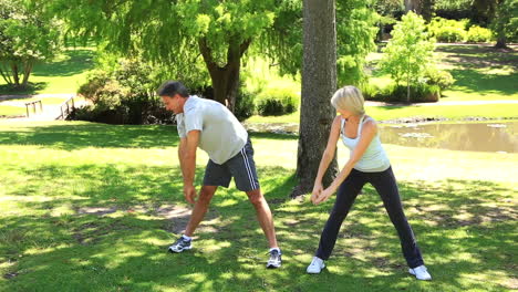 Couple-stretching-together-in-the-park