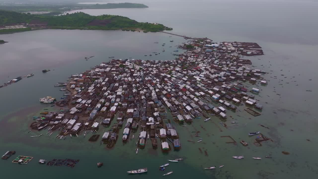 Perahu-perahu kecil tertambat di depan rumah-rumah pesisir, Pulau Bungin, Indonesia