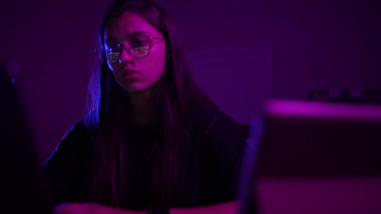 Woman Working on Laptop in a Dark Room with Neon Lights