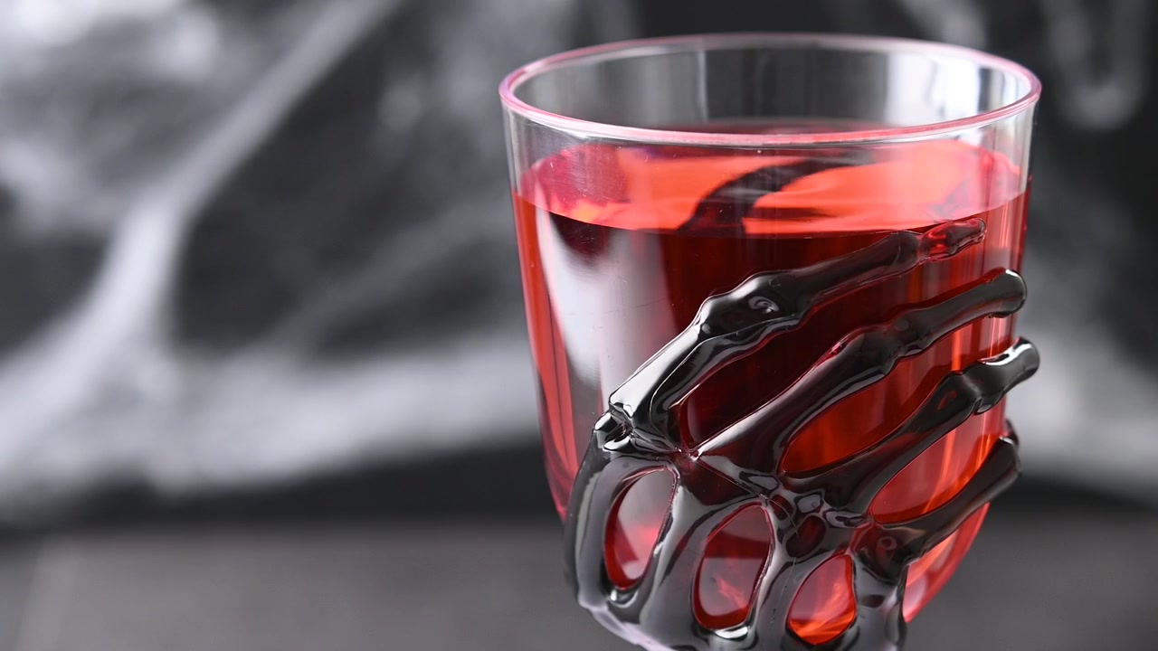 Cóctel de Halloween en un vaso con forma de mano de esqueleto.
