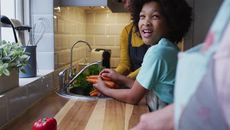 Mixed-race-lesbian-couple-and-daughter-preparing-food-in-kitchen