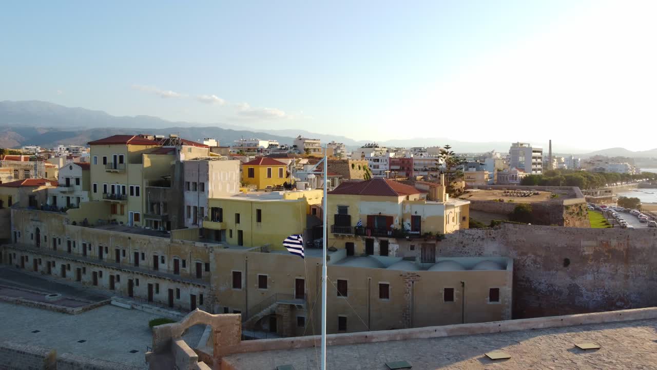 Greece national flag waving at Chania old town harbour, Crete, Drone shot, Panoramic view