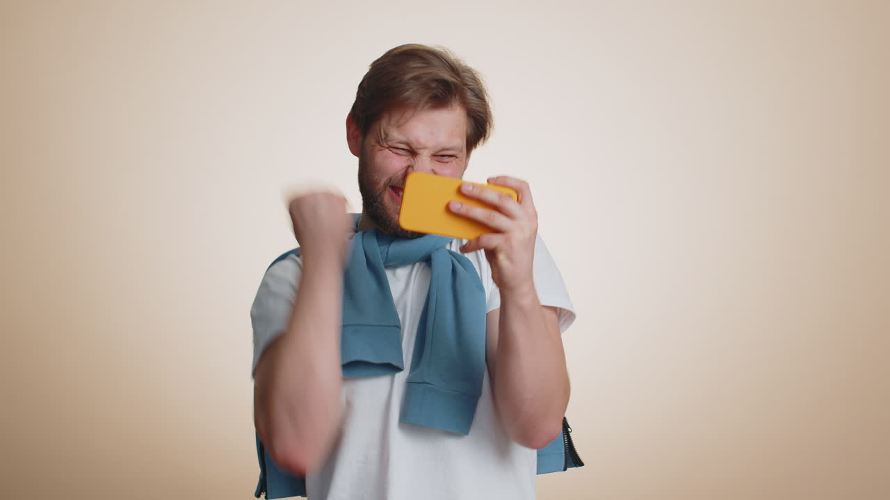 Worried funny addicted tourist guy enthusiastically playing drive racing video game on mobile phone