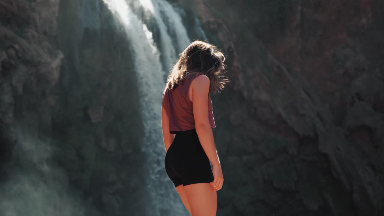 Detail of young caucasin woman walking in front of waterfalls in Ouzoud, Morocco