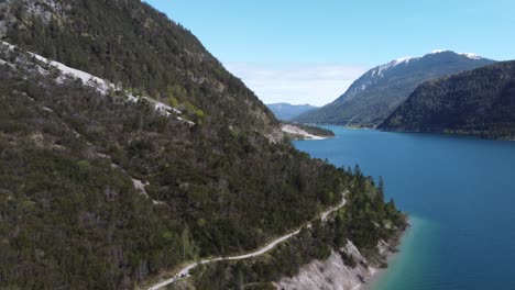 Vista-Aérea-De-Un-Hermoso-Sendero-De-Montaña-A-Lo-Largo-De-La-Costa-De-Un-Lago