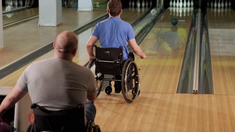 two young disabled men in wheelchairs playing bowling in the club