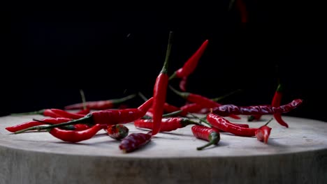 Slow-Motion-of-Red-Chili-Peppers-Dropped-Down-into-Cutting-Board,-then-Scattered