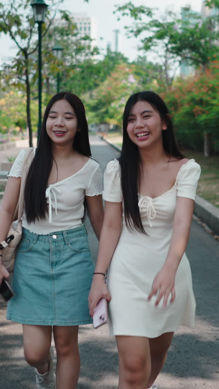 เพื่อนผู้หญิงสาวสองคนเดินเล่นในสวนสาธารณะอย่างมีความสุข