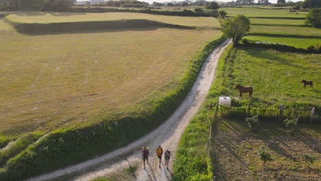 Aerial-View-Of-Group-Of-Three-Pilgrims-Walking-Together-On-Dirt-Road-On-A-Sunny-Day-3