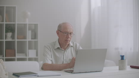 elderly man attorney is communicating with client by internet consulting by web camera sitting at table in office