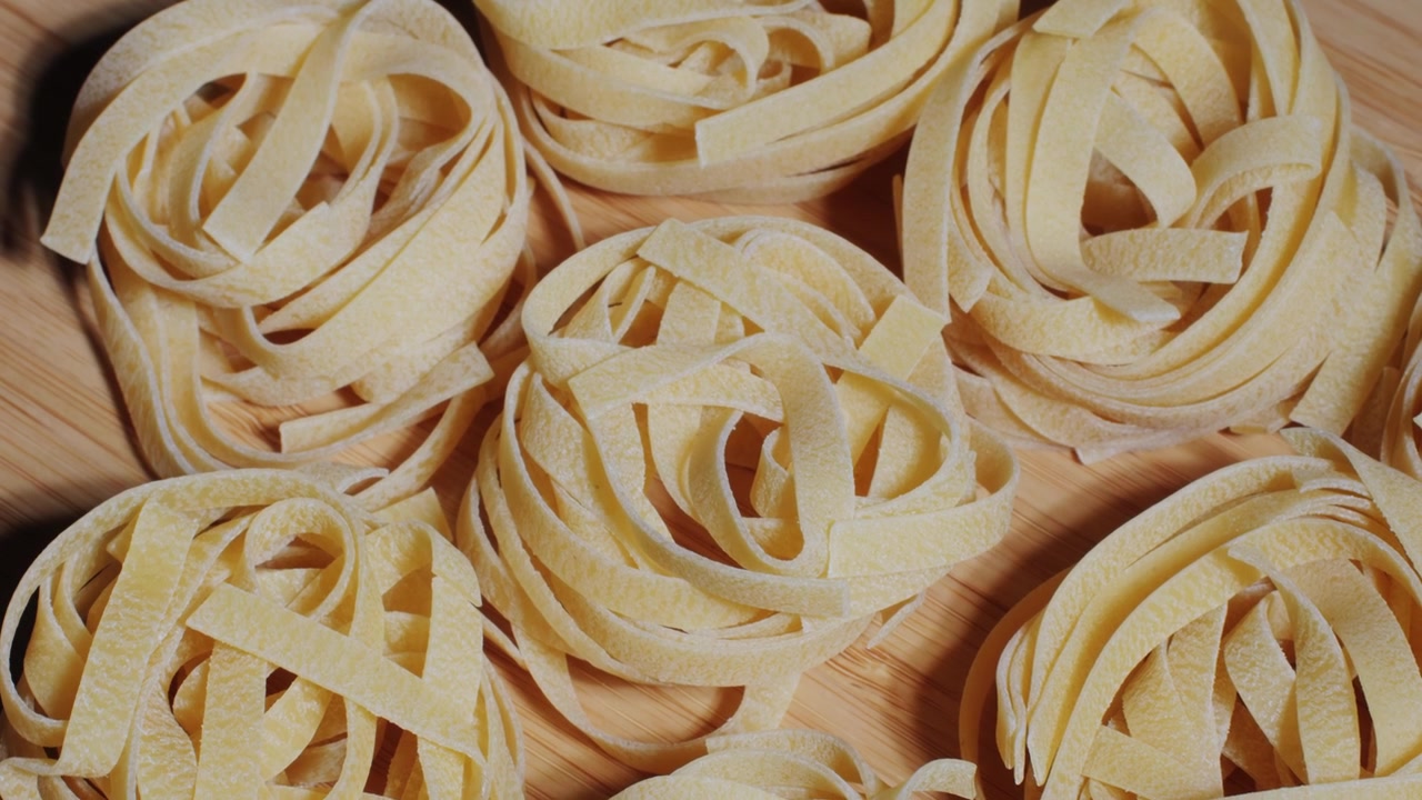 Primo piano di nidi di tagliatelle non cotte su una superficie di legno