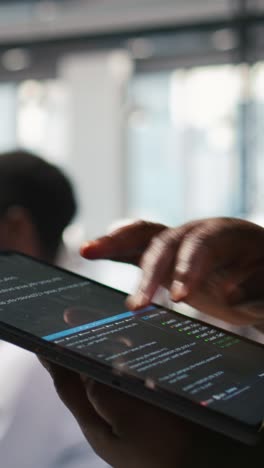 vertical video close up of programmer utilizing ai on tablet to optimize performance