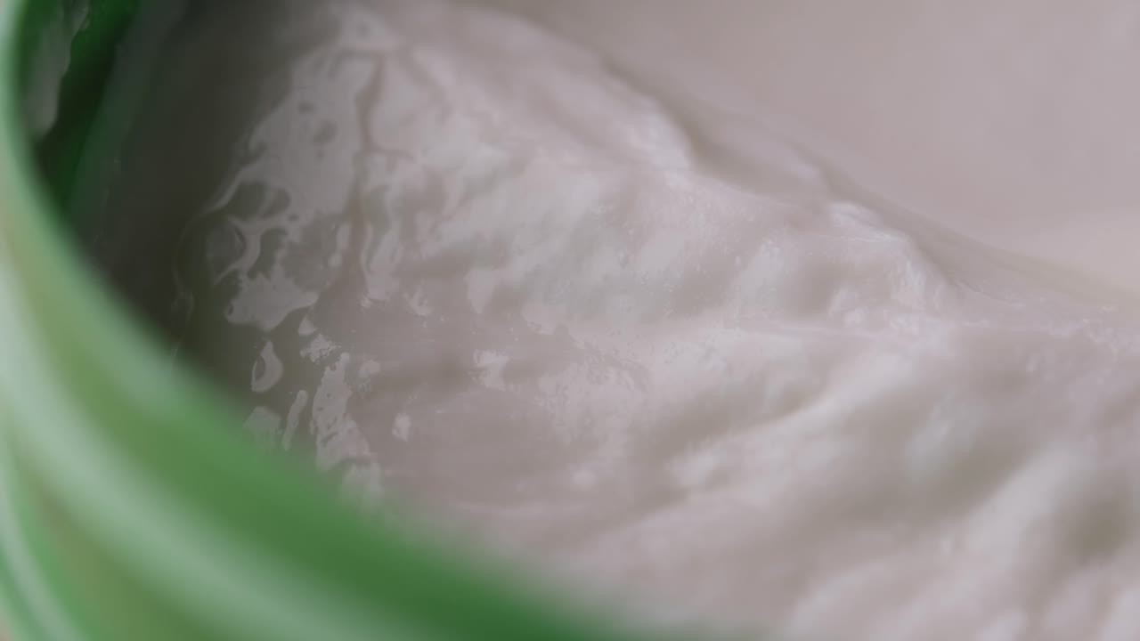 primer plano de una sustancia cremosa en un recipiente verde