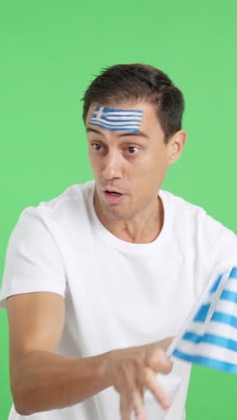man cheering for greece waving a national flag looking away