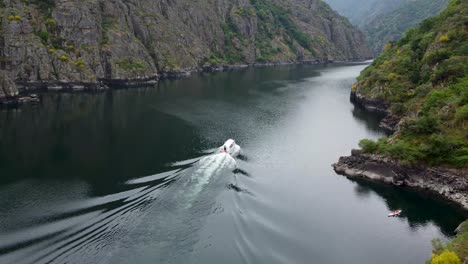 Aerial-tracking-of-tourist-boat-in-river-Sil-canyon,-Ribeira-Sacra