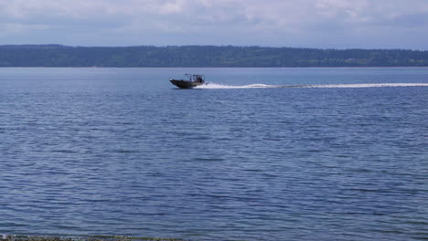 small, nondescript fishing boat cruising past beach at camano island state park, wa state