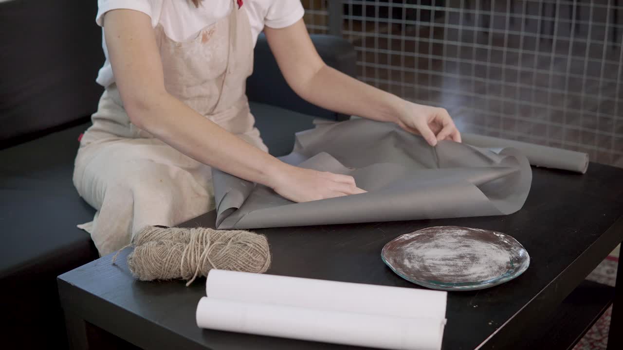 женщина упаковывает подарок.