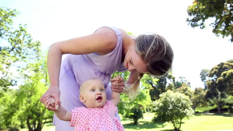 happy mother playing with her baby girl in the park