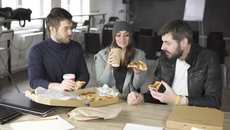 Eine-Gruppe-Junger-Designer-Unter-Der-Leitung-Des-Chefs-Arbeitet-An-Dem-Projekt-Des-Designbüros-Und-Isst-Gelieferte-Pizza-Und-Trinkt-Tee-Oder-Kaffee-In-Pappbechern.-Geschossen-In-4k